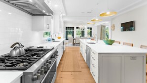 A modern kitchen with white cabinetry, a central island, stainless steel appliances, and pendant lighting. - Pristine getaway with tranquil views (Kiawah Island)