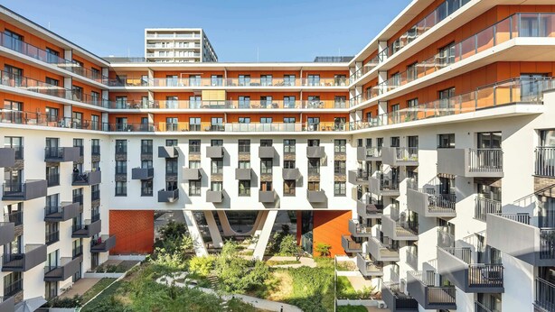 Un edificio residencial de varios pisos con balcones, un patio central y un diseño arquitectónico moderno.