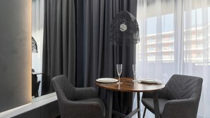 Una habitación moderna con dos sillones grises tapizados, una mesa redonda de madera y una lámpara colgante trenzada negra.