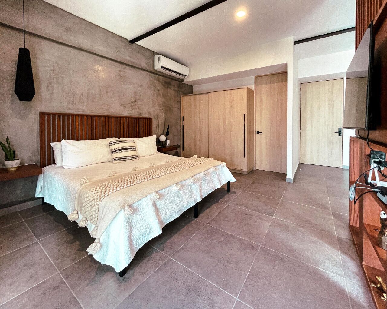 Camera da letto moderna con un letto grande, una testiera in legno e un armadio a muro.
