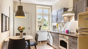 A kitchen with a dining table, chairs, a hanging light fixture, cabinets, an oven, and a refrigerator. - Apartment '1' with Private Terrace, Shared Garden and Wi-Fi (Groß Pankow)