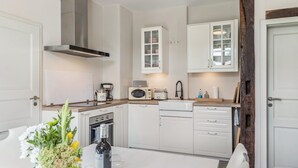 Een keuken met witte kastjes, een roestvrijstalen afzuigkap, een magnetron en een broodrooster.