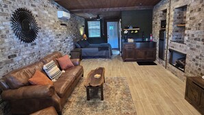 Una sala acogedora con pared de ladrillo, techo de madera y chimenea.