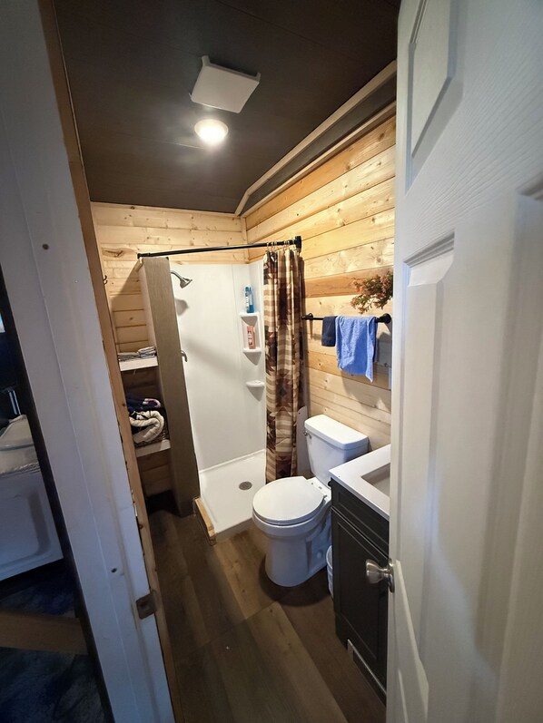 Une petite salle de bain comprenant une douche, des toilettes et un lavabo.