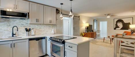 A modern kitchen with stainless steel appliances, white cabinetry, and pendant lighting.