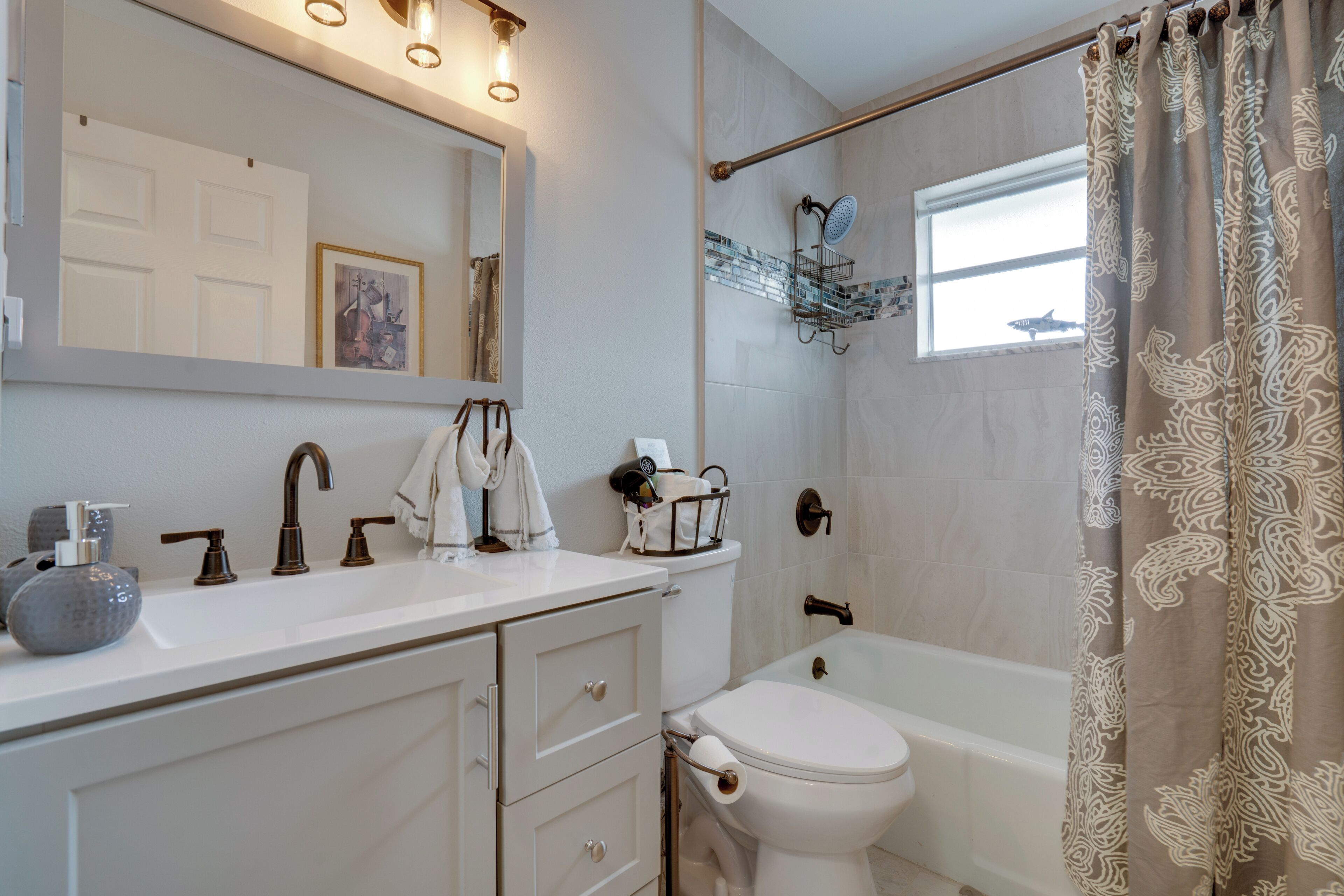Ein Badezimmer mit weißem Waschbecken, Toilette, Badewanne und Duschvorhang.