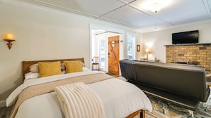 A hotel room with a bed, a sofa, a television, and a fireplace.