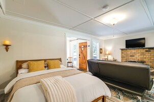 Una habitación de hotel con una cama, un sofá, un televisor y una chimenea.
