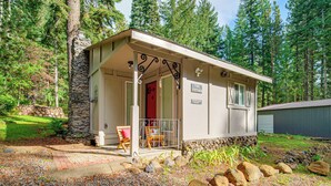A cabin with a stone exterior, a porch with a red door, and a sign reading "The Cottage."