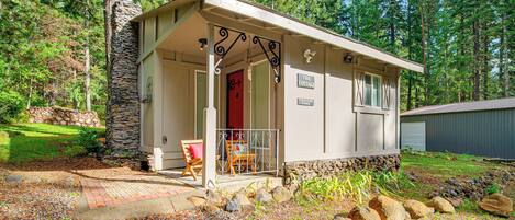 A cabin with a stone exterior, a porch with a red door, and a sign reading "The Cottage."