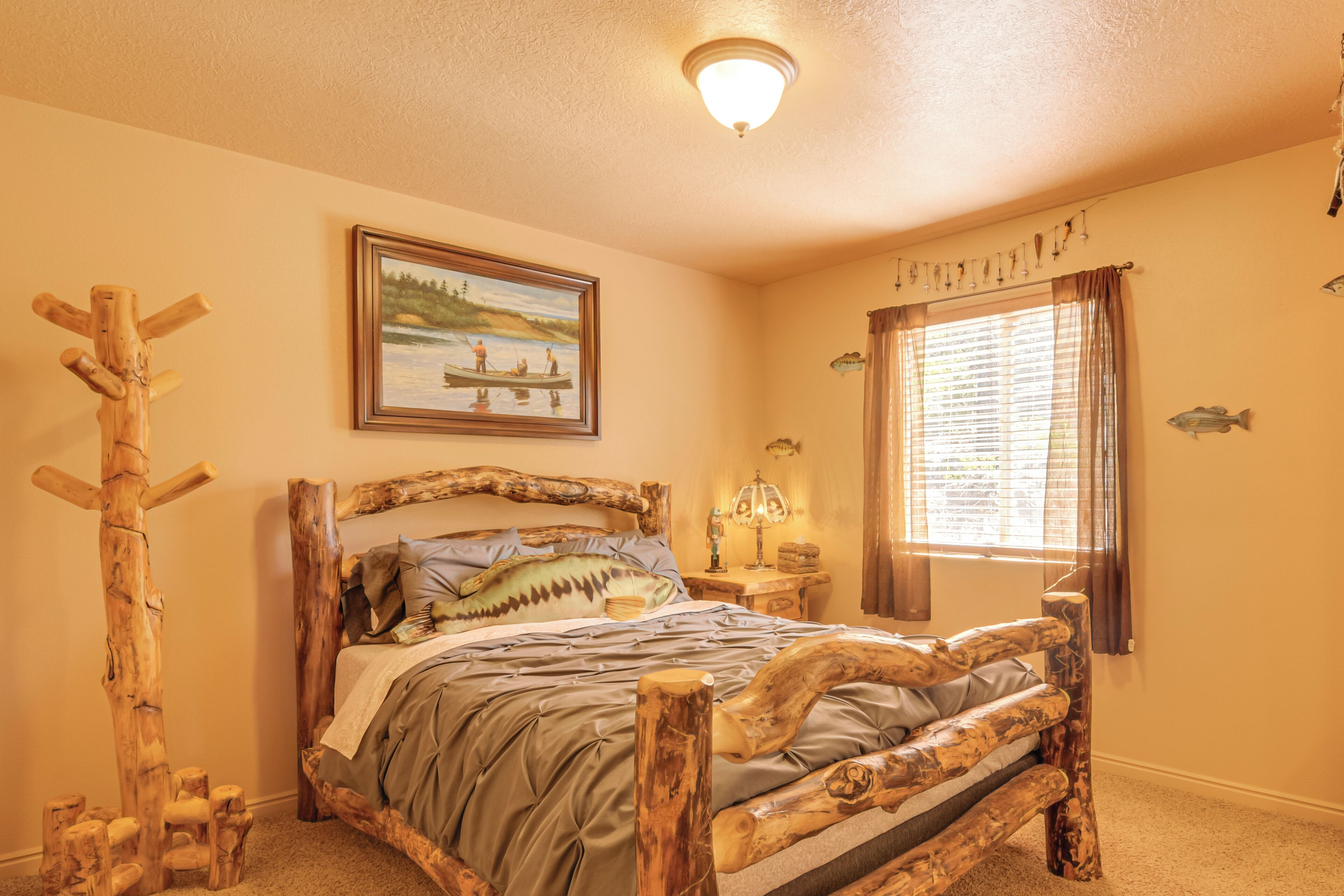 Une chambre à coucher avec un lit en bois au style rustique, un tableau représentant un paysage lacustre et une fenêtre avec des rideaux.