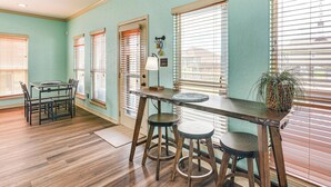 A dining area with a wooden table, two stools, and a lamp. - Walk to the Ocean: Family Retreat in Crystal Beach (Port Bolivar)