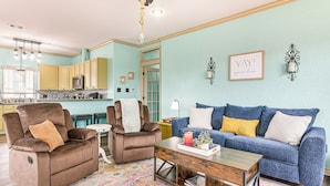 A living room with a blue sofa, two brown recliners, a wooden coffee table, and a colorful rug. - Walk to the Ocean: Family Retreat in Crystal Beach (Port Bolivar)