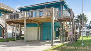 A two-story building with a balcony, a garage, and a signboard. - Walk to the Ocean: Family Retreat in Crystal Beach (Port Bolivar)