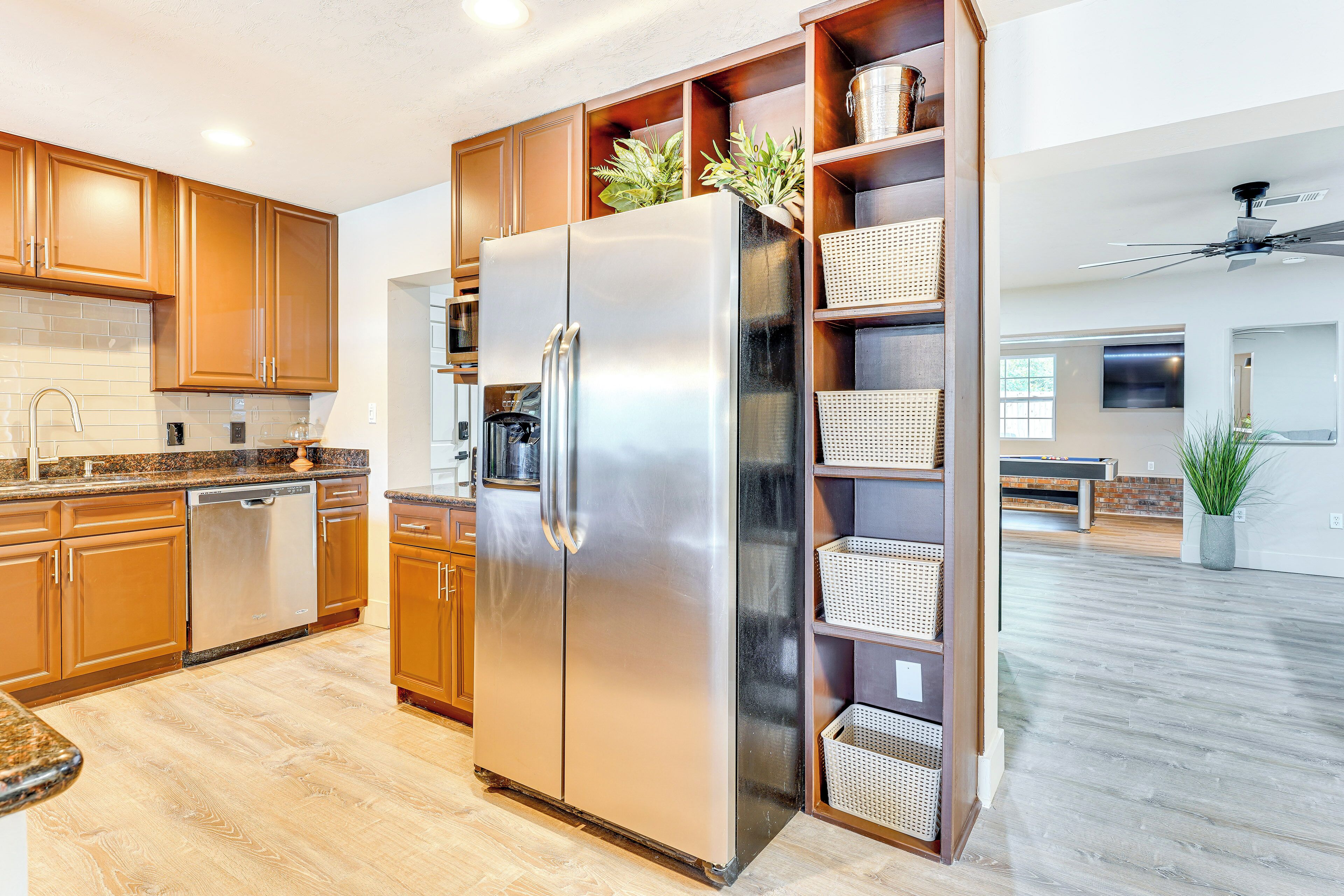 A modern kitchen with stainless steel appliances, wooden cabinets, and built-in wicker baskets.