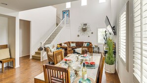 A spacious living area with a dining table set for four, a staircase, and a cozy seating area with a sofa and chairs. - Walk to Beach: Luxe San Buenaventura Villa! (Port Hueneme)