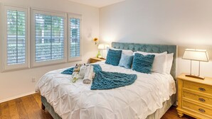 A bedroom with a large bed, two bedside tables, a nightstand, and a window with blinds. - Walk to Beach: Luxe San Buenaventura Villa! (Port Hueneme)