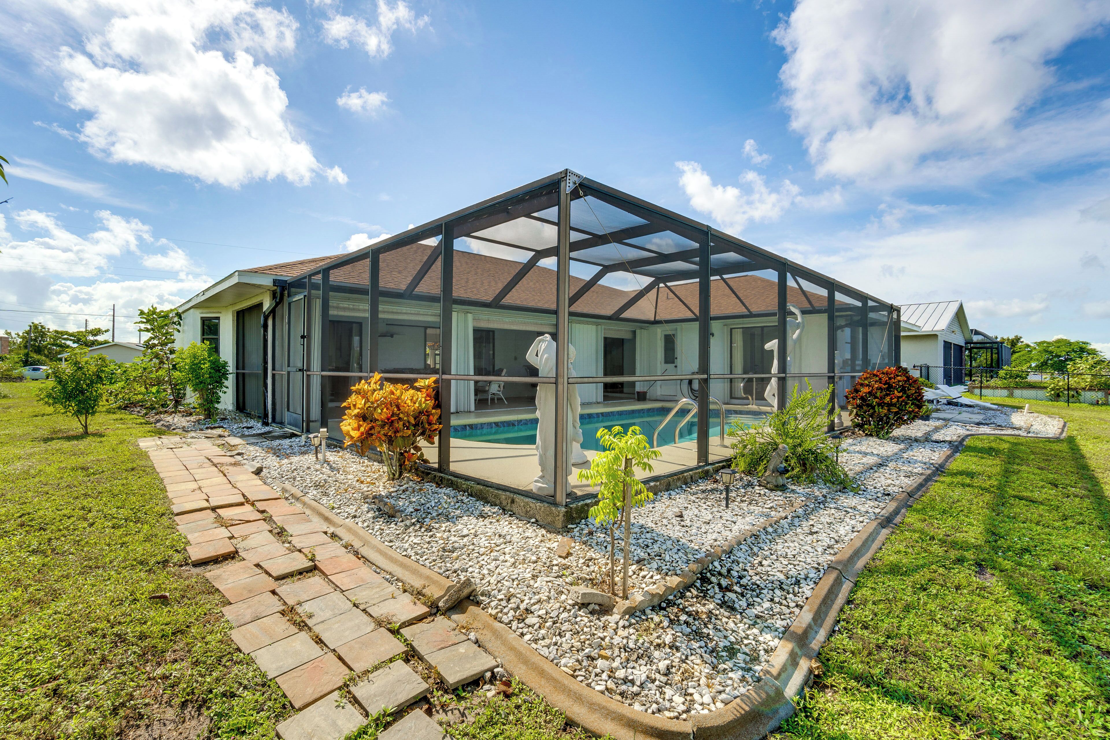 A modern house with a glass-enclosed patio, a swimming pool, and a well-maintained garden.