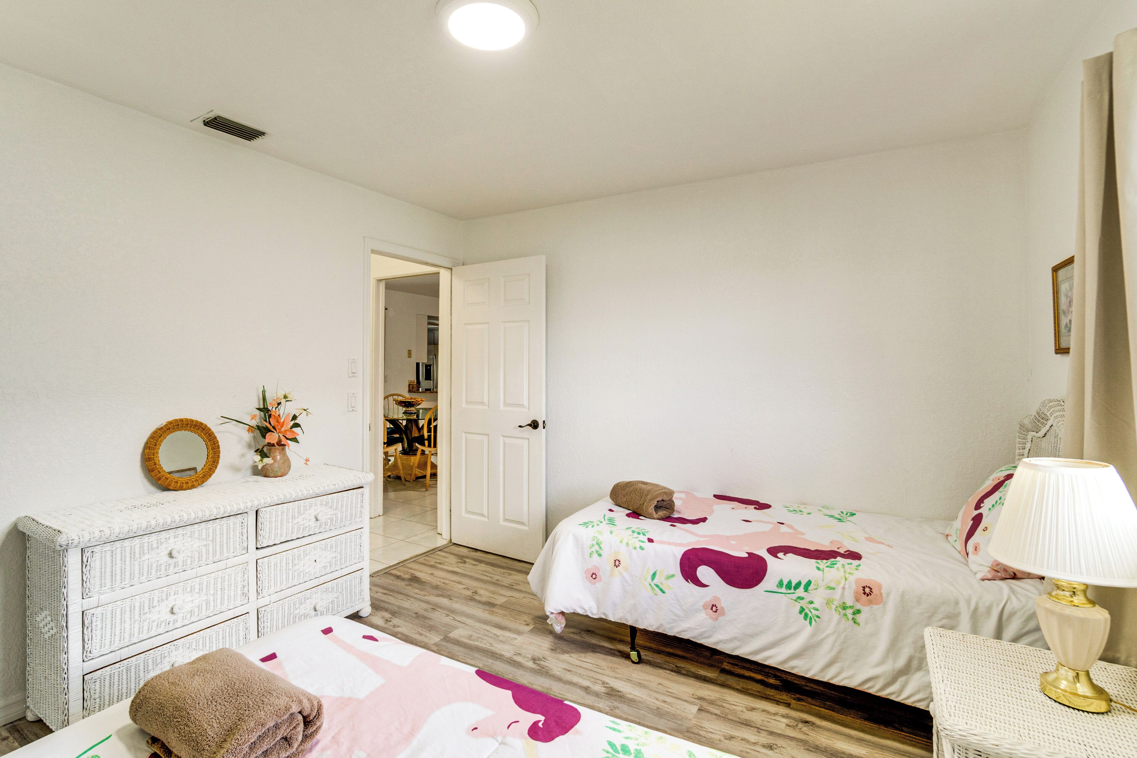Ein Schlafzimmer mit einem Bett, einem Schminktisch, einer Lampe und einer Tür zu einem anderen Raum.