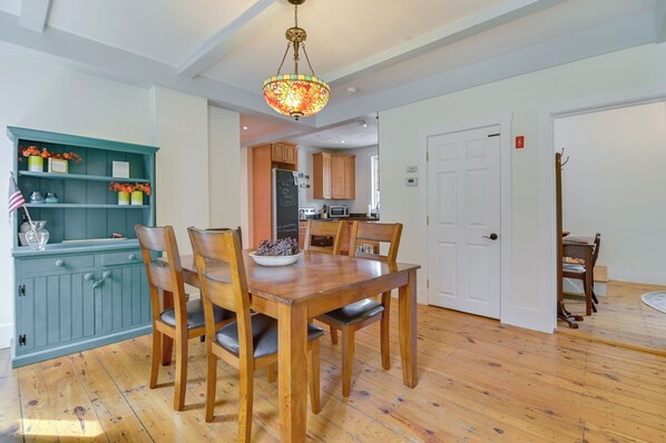 A dining area with a wooden table and chairs, a teal cabinet with decorative items, and a kitchen in the background. - Lake Access + Views: Family Getaway in Conway! (Conway)