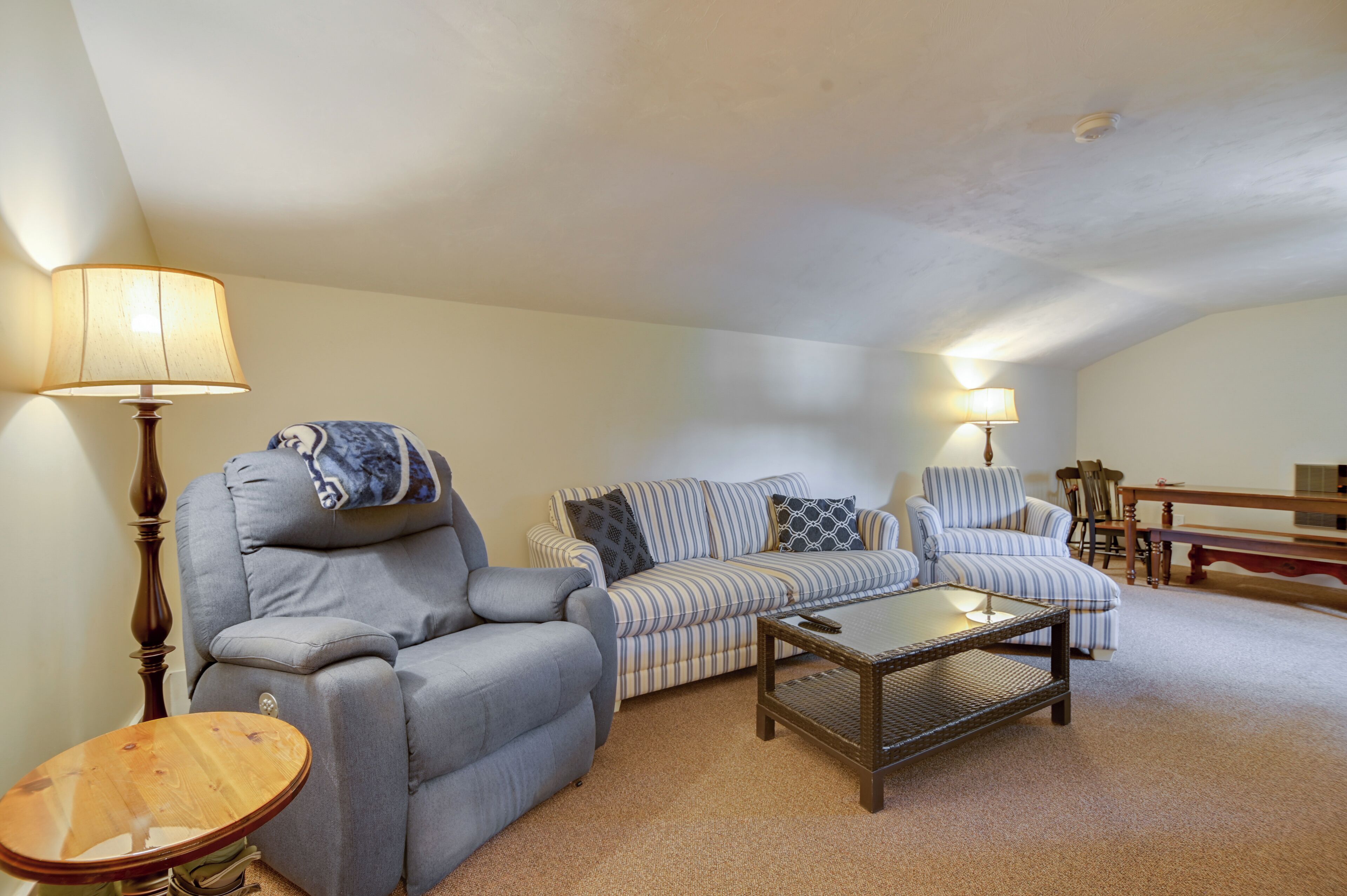 A living room with a sofa, armchairs, a coffee table, and lamps.