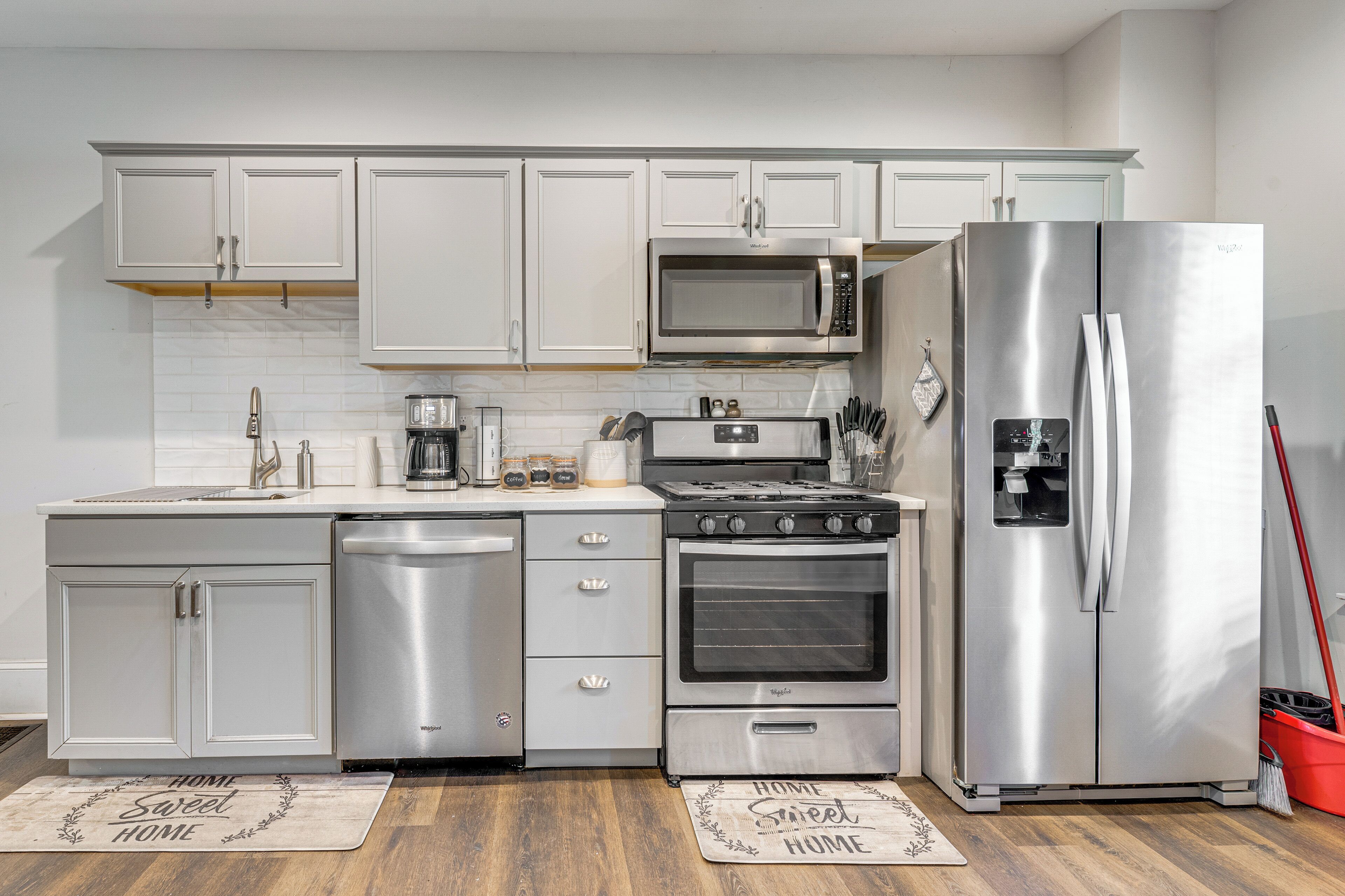Una cocina moderna con electrodomésticos de acero inoxidable, armarios blancos y suelo de madera.