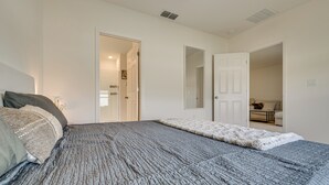 A bedroom with a large bed, a door leading to another room, and a mirror on the wall. - Easy Disney Day Trips: Family Home w/ Pool Access (Groveland)
