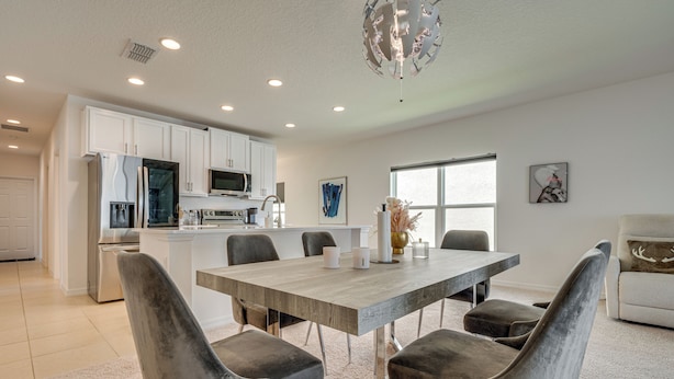 A modern kitchen with white cabinets, a stainless steel refrigerator, and a microwave. - Easy Disney Day Trips: Family Home w/ Pool Access (Groveland)