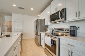 A modern kitchen with white cabinets, stainless steel appliances, and a large island with a sink.
