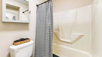A bathroom with a toilet, a shower curtain, and a bathtub.