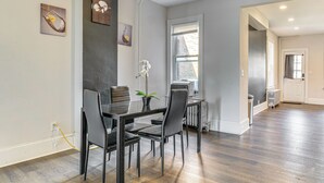 Een eethoek met een tafel, stoelen, een kamerplant en kunstwerken aan de muur.
