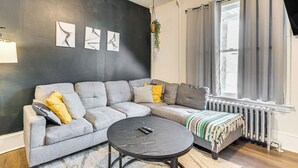 A modern living room with a grey sectional sofa, a round coffee table, and a radiator. - 9 Mi to Shawnee Mtn! Stroudsburg Unit Near Main St (Stroudsburg)