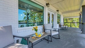 Eine überdachte Terrasse mit weißen Backsteinmauern, großen Fenstern und Sitzgelegenheiten im Freien.