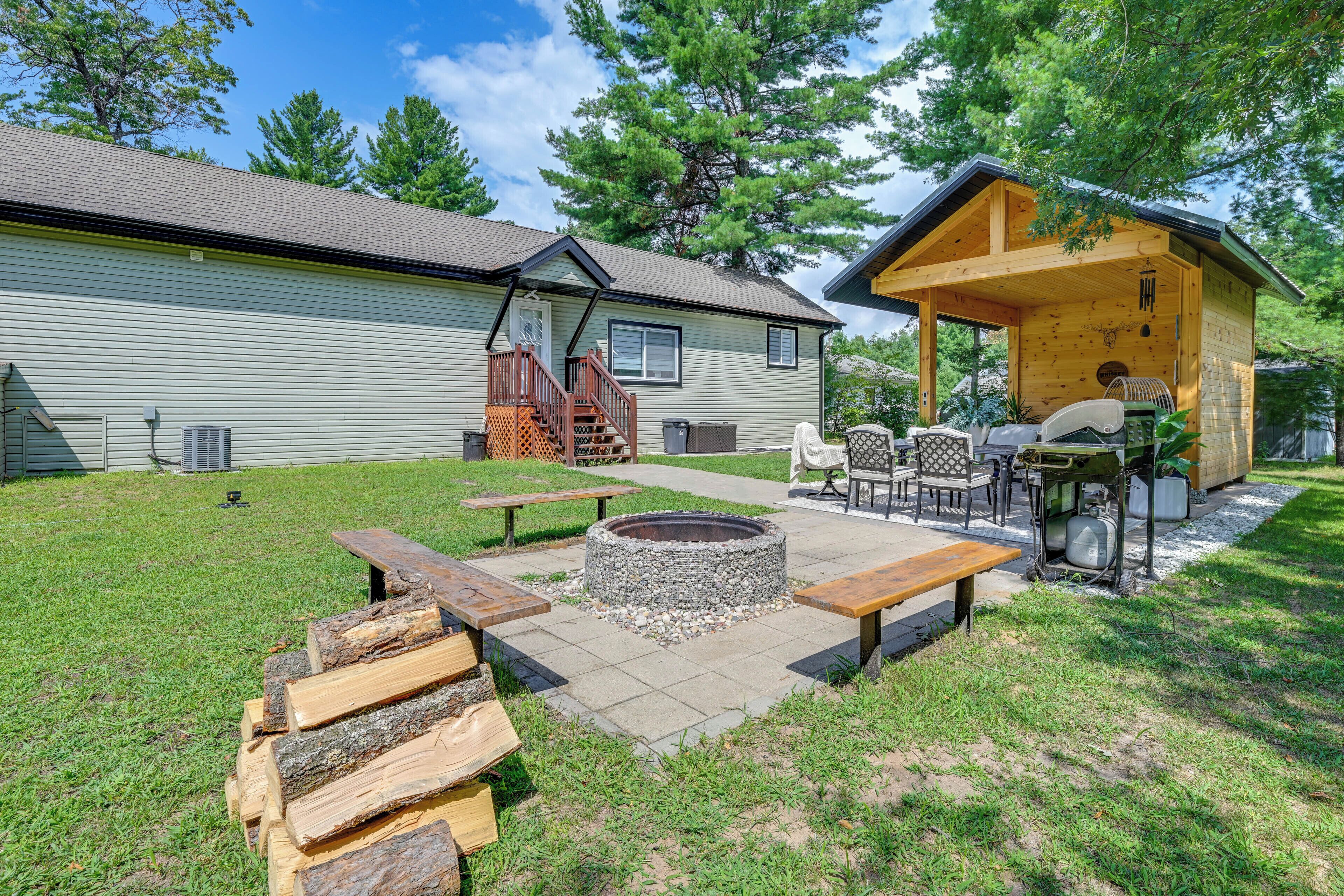 A backyard with a fire pit, picnic tables, and a covered seating area with a table and chairs.