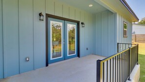 A light blue building with a covered porch and a black railing. - 1 Mi to Lake Lbj: Peaceful Home w/ Patio & Yard! (Marble Falls)