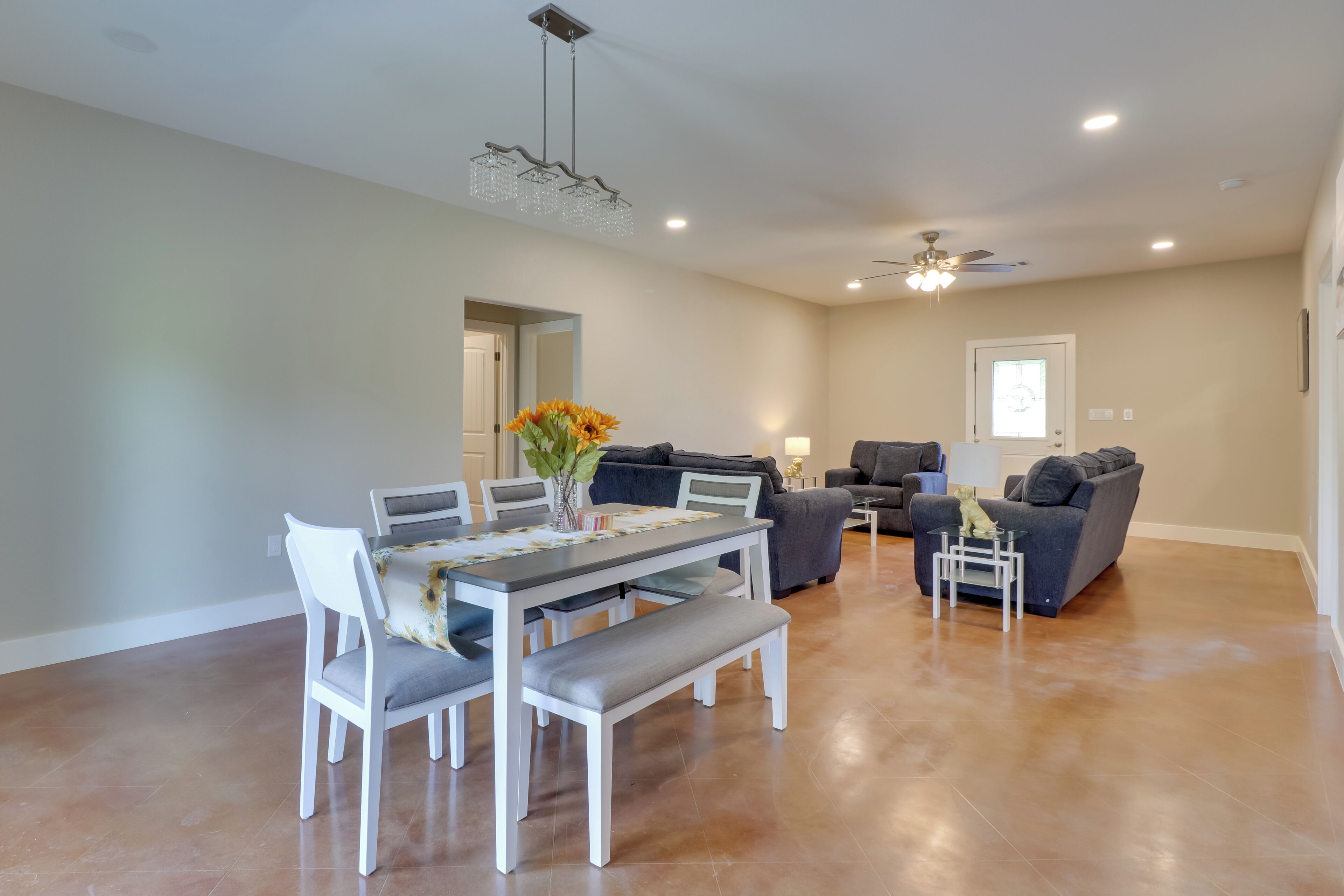 A spacious living area with a dining table, sofas, and a ceiling fan.