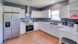 A modern kitchen with white cabinets, a stainless steel refrigerator, an oven, a sink, and a microwave. - 1 Mi to Lake Lbj: Peaceful Home w/ Patio & Yard! (Marble Falls)