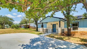 A residential house with a stone facade, a blue door, and a driveway leading to the entrance. - 1 Mi to Lake Lbj: Peaceful Home w/ Patio & Yard! (Marble Falls)