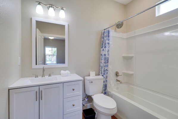 Une salle de bain avec un lavabo blanc, un miroir, des toilettes et une baignoire.