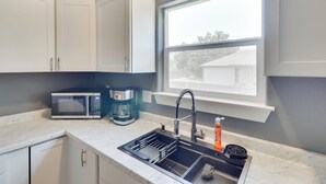 Eine moderne Küche mit weißen Schränken, einer eingebauten Mikrowelle, einer Kaffeemaschine und einem Spülbecken mit Armatur.