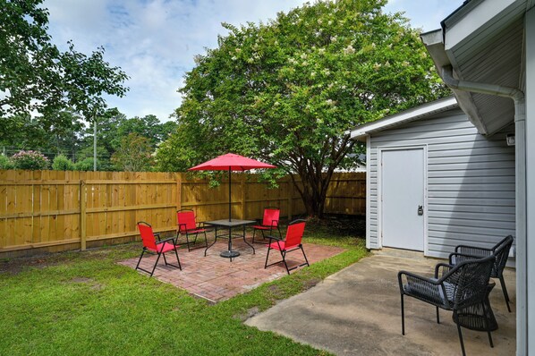 A backyard patio with a red umbrella, four red chairs, and a table. - Game Day Ready: Greenville Stay w/ Patio Dining (Greenville)