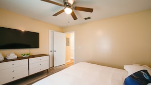 A bedroom with a bed, a ceiling fan, a TV mounted on the wall, and a door leading to another room. - Game Day Ready: Greenville Stay w/ Patio Dining (Greenville)