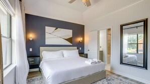 A bedroom with a large bed, bedside tables, a ceiling fan, and a large mirror. - Yard & Workspaces: Luxe Duplex Unit in Houston (Houston)