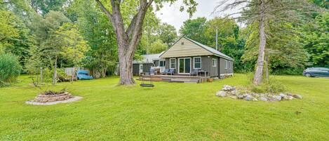 A house with a deck, surrounded by a grassy yard and trees.
