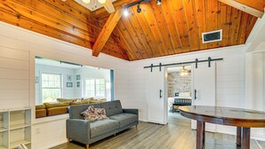 Un salon spacieux avec un plafond en bois, un canapé gris et une table à manger en bois.