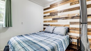 A bedroom with a bed, a nightstand, a wooden headboard, and a window with curtains. - Private UP Escape Near Lake Superior (Pelkie)