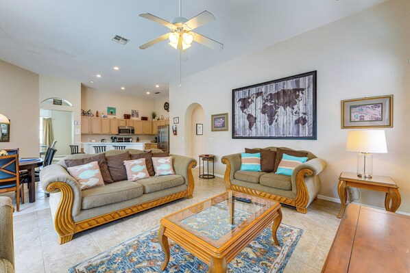 A spacious living room with two sofas, a coffee table, and a dining area in the background.