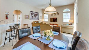A dining area with a wooden table set for four, surrounded by leather chairs. There is a hanging light fixture above the table. - Heated Pool, 9 Mi to Disney: Davenport Haven! (Davenport)
