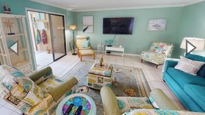 A living room with teal walls, a TV, and a sofa.