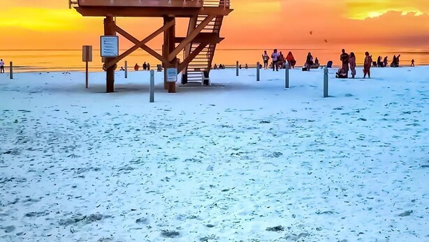 A lifeguard tower on a beach with a sunset in the background.